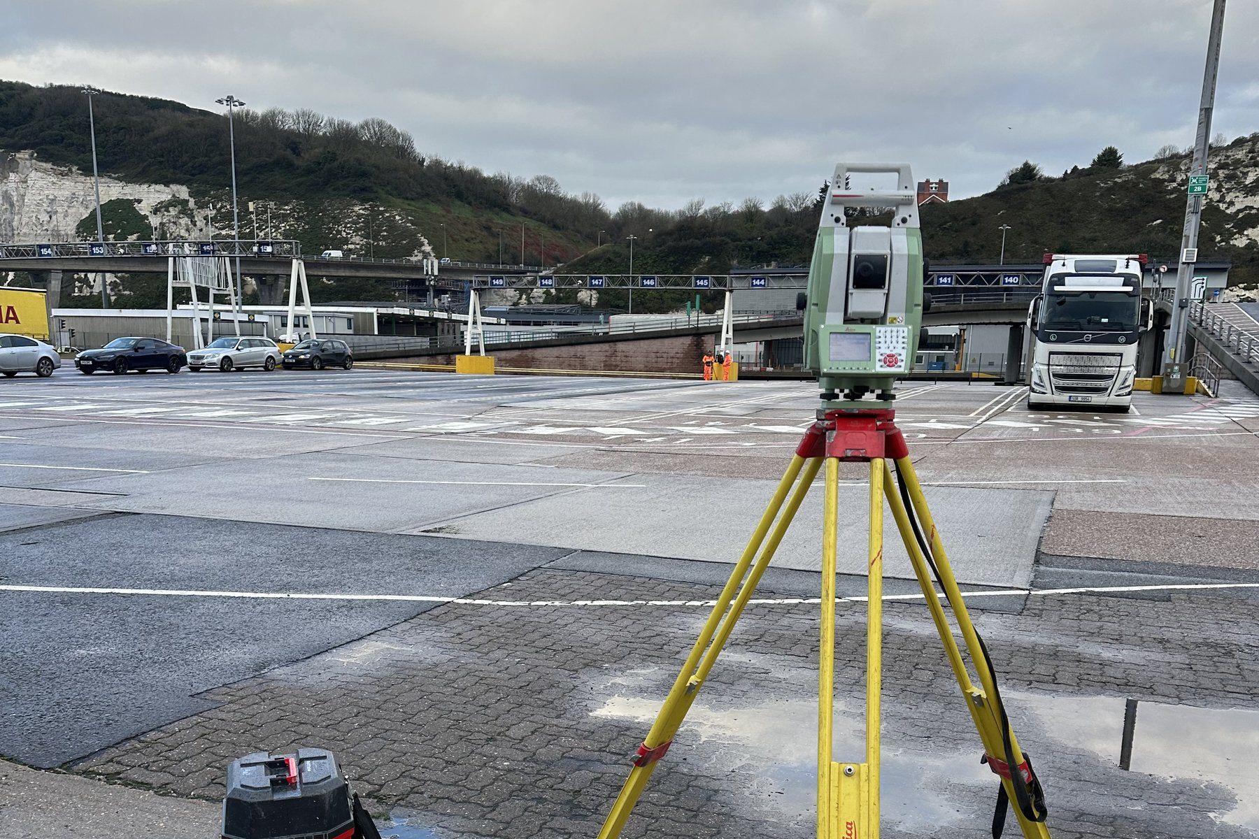 Total station on tripod at a port with chalk cliffs behind